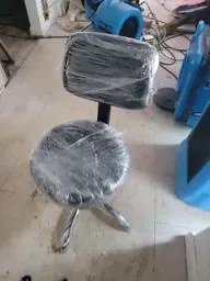 Shrink-wrapped stool beside air movers on a mitigation site